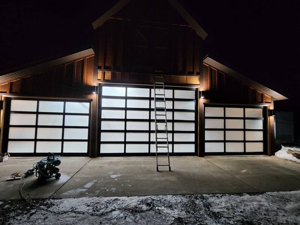 Modern garage with frosted glass doors, ladder, and exterior lighting at night.