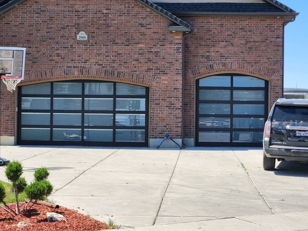 Modern brick house with two large glass garage doors and an SUV parked in the driveway.
